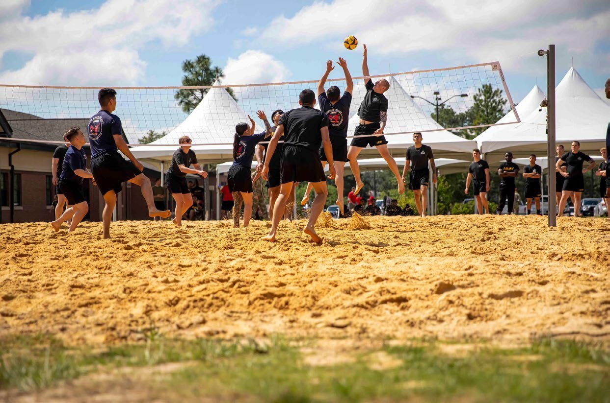 Troops playing volleyball at a base camp recreation event.