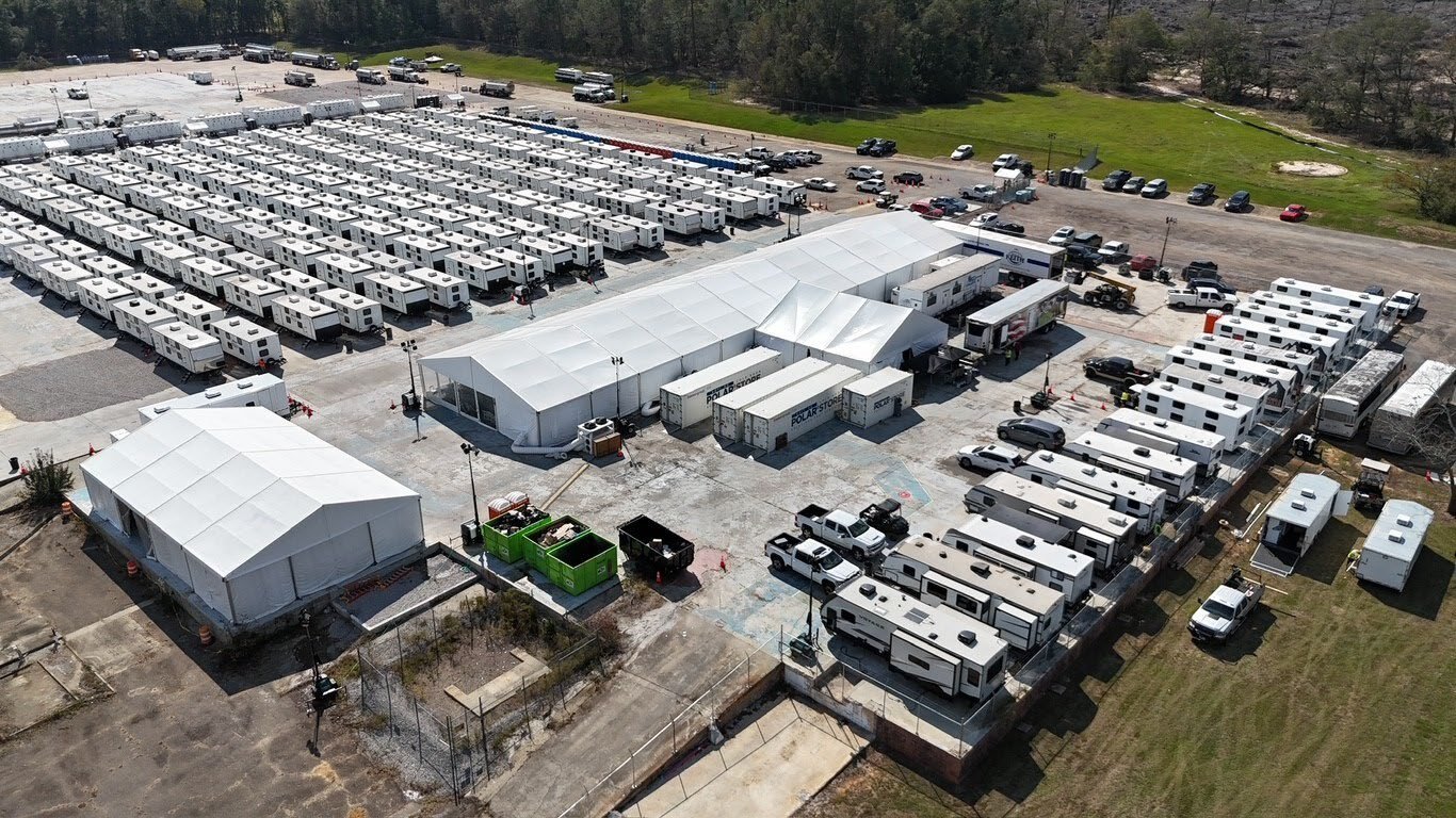 Aerial view of a fully built workforce camp with housing units, dining and support tents, and site infrastructure arranged on a single managed site.
